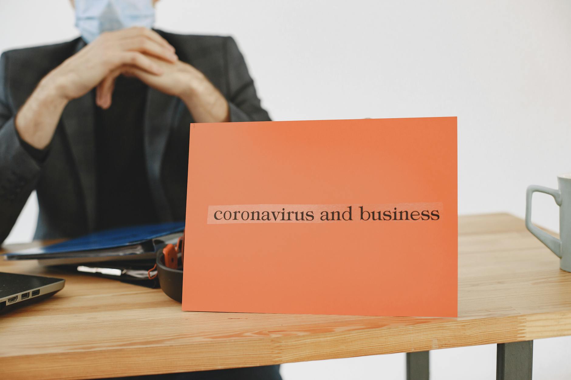 Biznesmen trzyma tabliczkę z napisem coronavirus impact