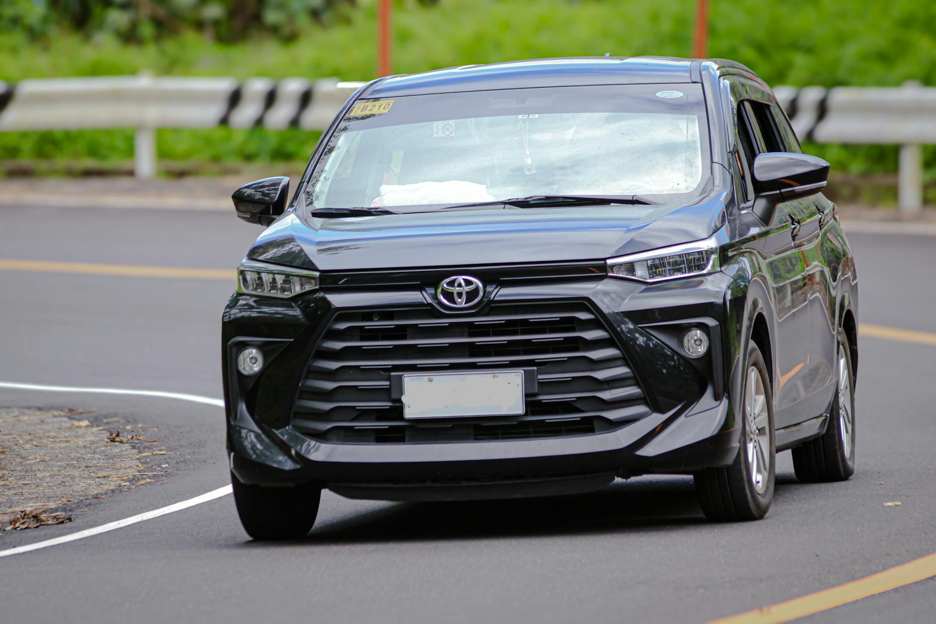 Czarny minivan jedzie po miejskiej ulicy w słoneczny dzień