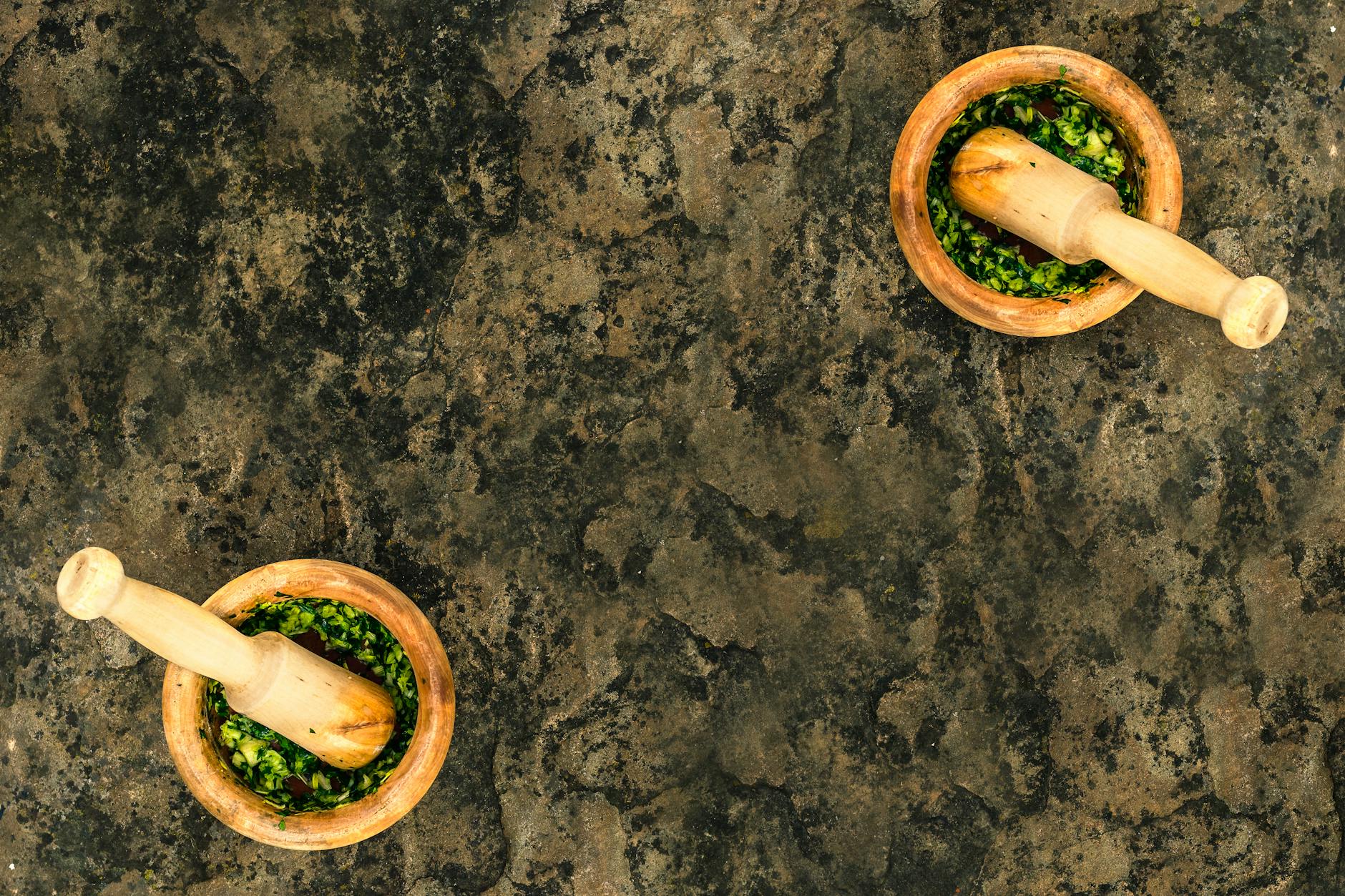 Drewniane moździerze z domowym zielonym pesto bazyliowym widziane z góry