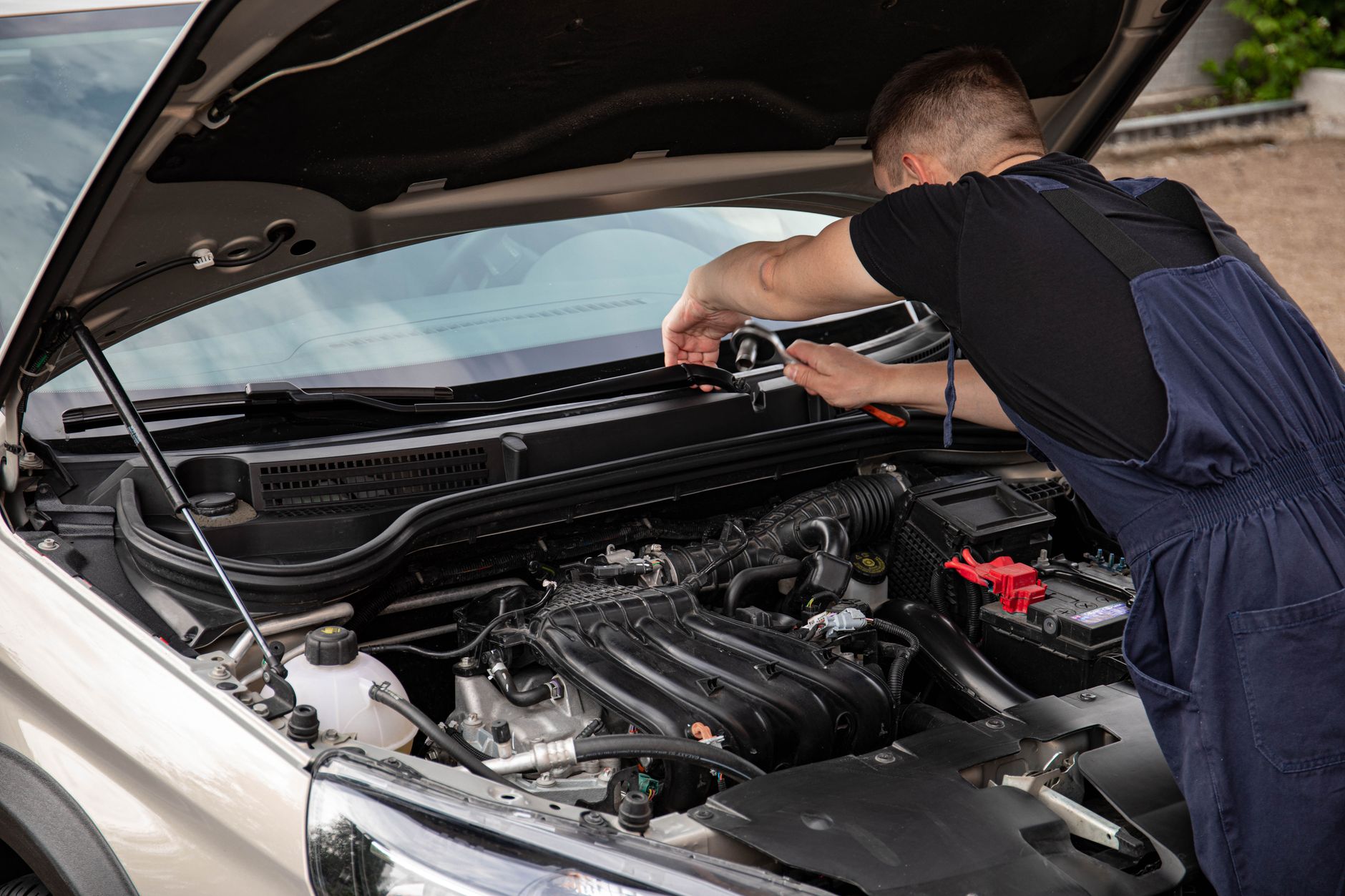 Jak sprawdzić Cadillaca z ogłoszenia, zanim pojedziesz kilkaset kilometrów Mechanik naprawia silnik samochodu na zewnątrz w ciągu dnia